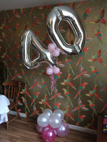 Large forty shaped balloon design in silver and pink standing on floor.