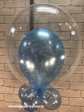 Blue communion printed balloon placed inside a clear bubble balloon.