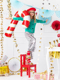 Child with red and white candy cane balloon standing on red chair.
