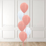Rose gold and white balloons against a brick wall background.