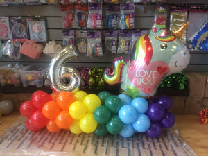 Multicolour balloon design with a unicorn balloon and silver number six balloon.
