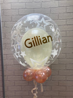 Ivory and rose gold coloured personalised balloon against brick wall.