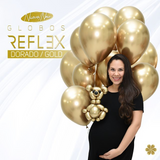 Pregnant woman holding shiny gold balloons.