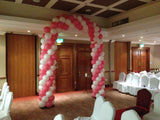 Pink and white double balloon arch on metal stand.
